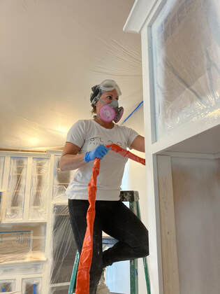 Bloom team member spraying paint on cabinet frames.